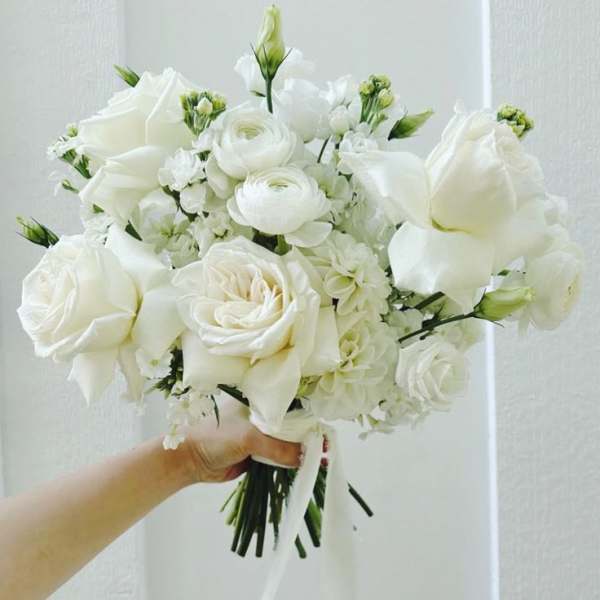 White rose bouquet with small white blooms and ribbon handle