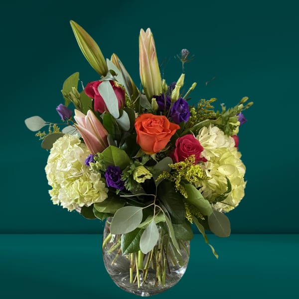 Mixed bouquet with roses, lilies, and hydrangeas in a glass vase
