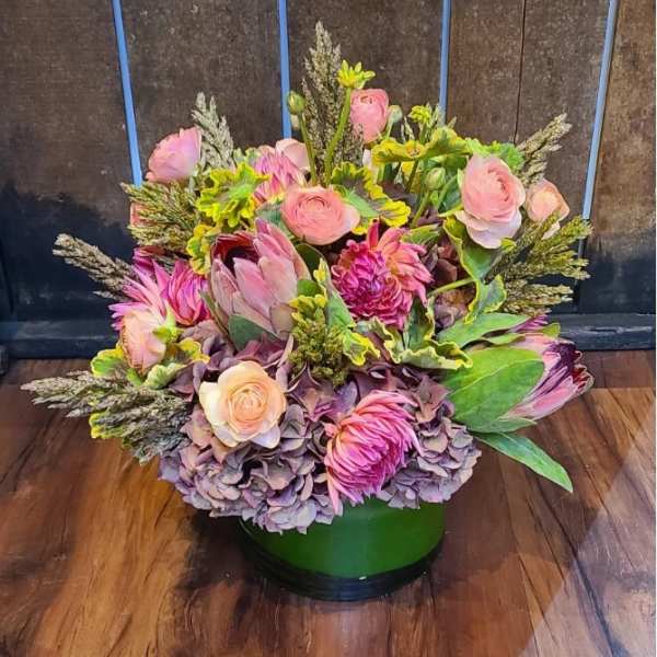 Pink and lavender floral arrangement in a green vase