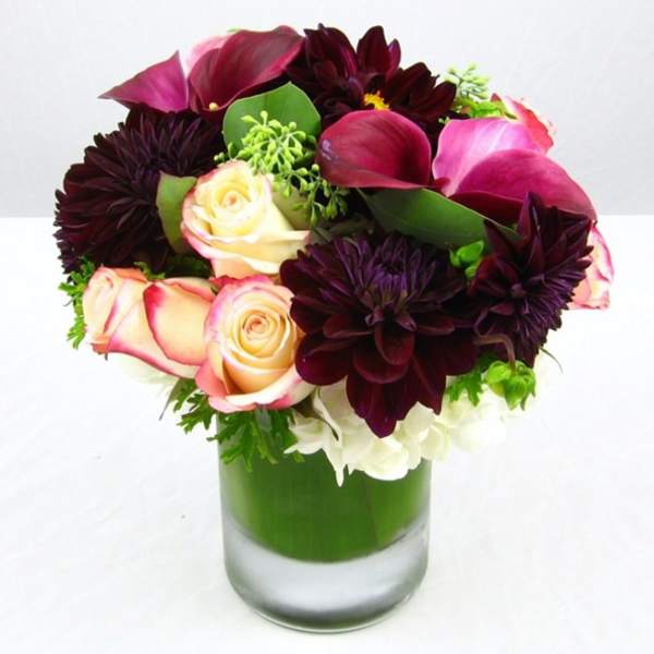 Bouquet of dark purple flowers and pink roses in a glass vase