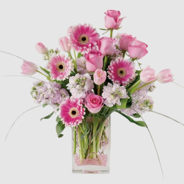 Pink roses and gerbera daisies in a clear rectangular vase