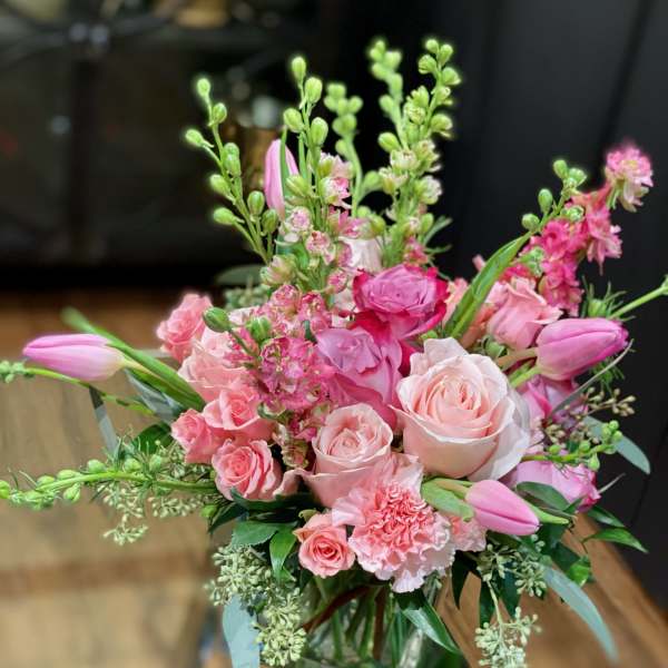 Pink roses and tulips arranged in a clear glass vase