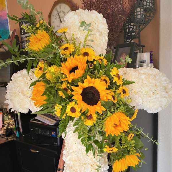 White floral cross with yellow sunflowers on an easel