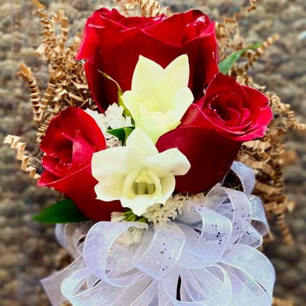 Red roses and white orchids with a sheer ribbon bow