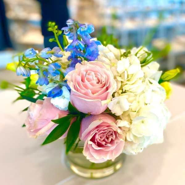 Pink roses with blue and white flowers in a glass vase