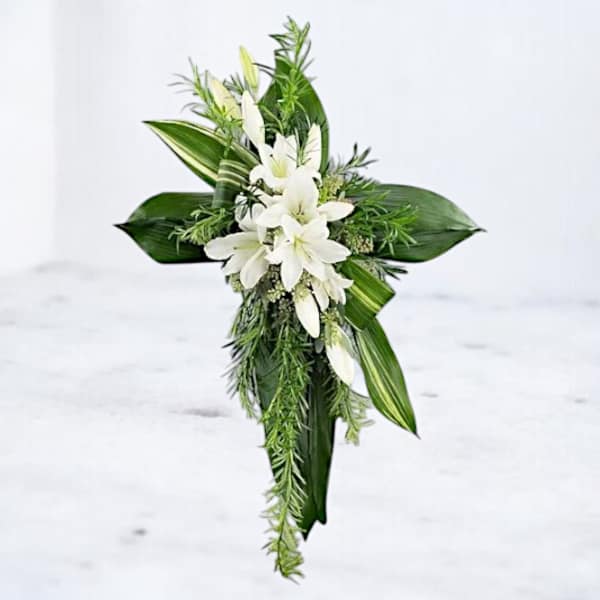 White lilies with long green leaves in a cross-shaped arrangement