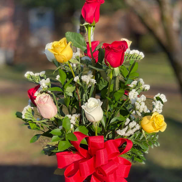 Mixed roses in a glass vase with a red ribbon bow