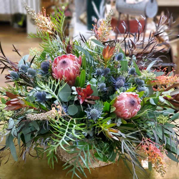 Large mixed floral arrangement with pink protea in a low container