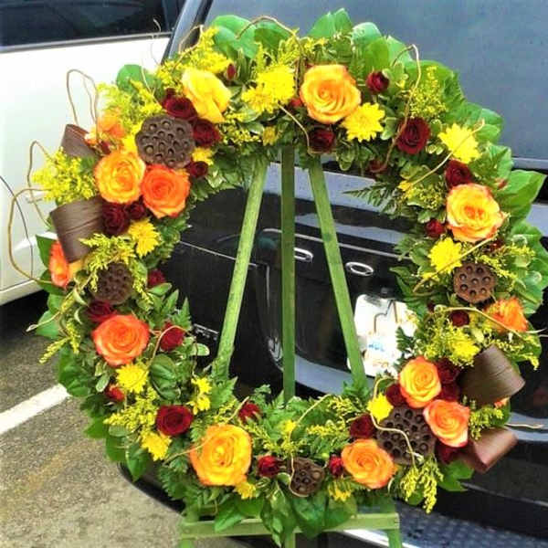 Large floral wreath with orange and red roses and yellow blooms