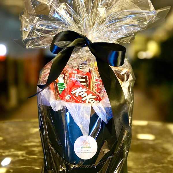Gift basket with assorted candy wrapped in clear cellophane and a black ribbon