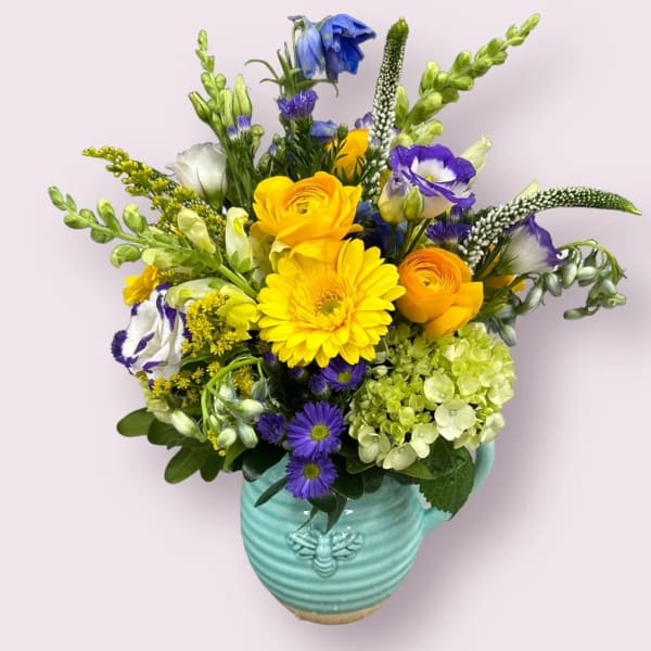Mixed bouquet in a turquoise vase with yellow, purple, white, and green blooms