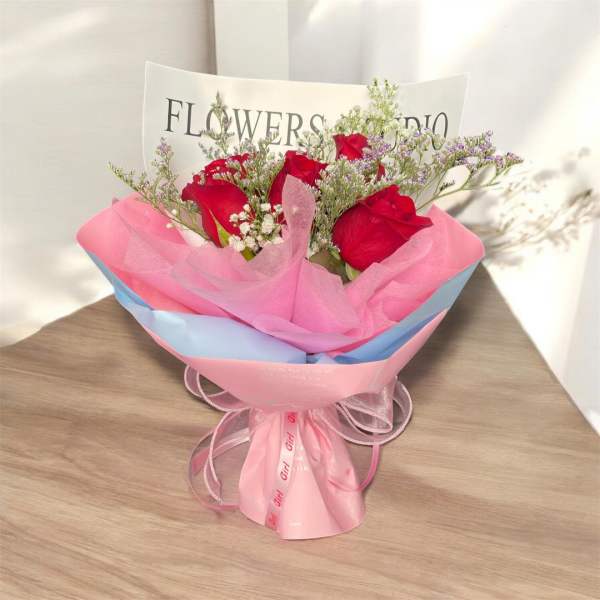 Bouquet of red roses wrapped in pink and blue paper