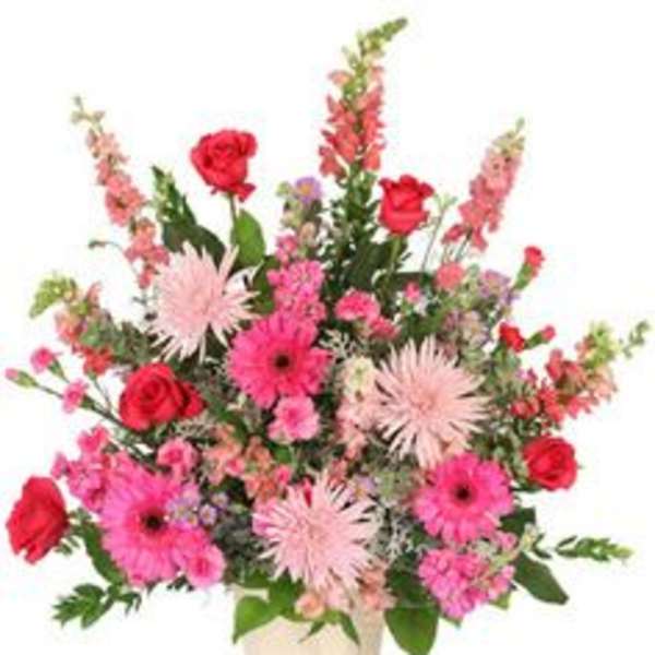 Pink and red mixed flower arrangement in a cream ceramic container