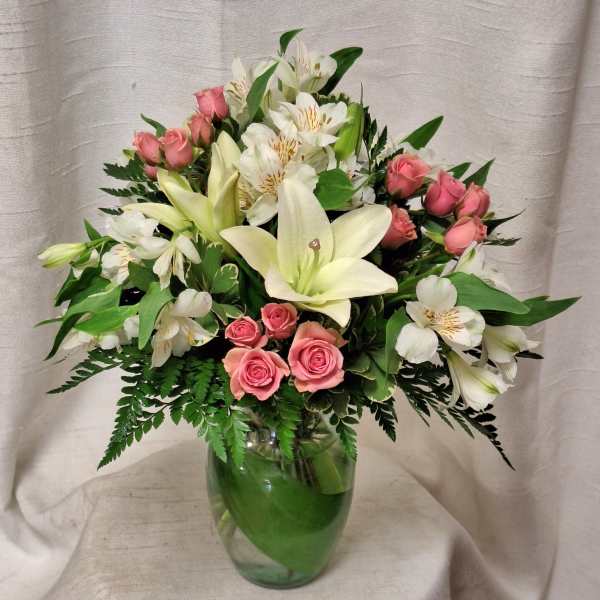 Pink roses and white lilies arranged in a clear glass vase