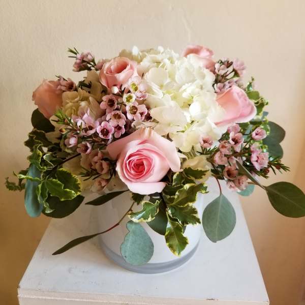 Pink roses and white hydrangeas arranged in a white vase