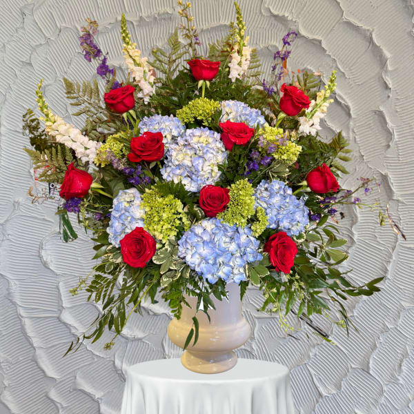 Large bouquet of red roses and blue hydrangeas in a white vase
