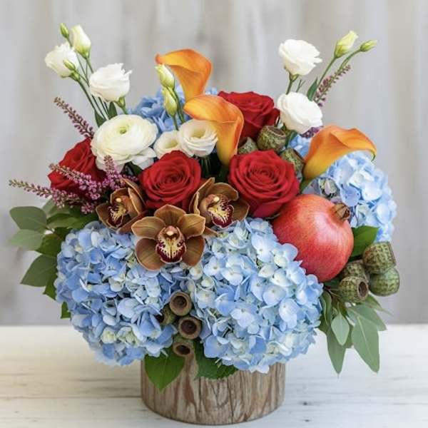 Mixed bouquet with blue hydrangeas, red roses, orange calla lilies, and white blooms in a wood-look container