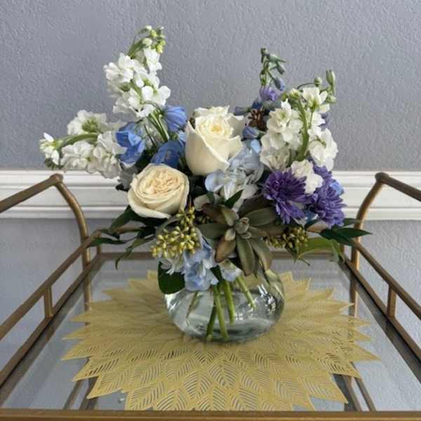 Mixed bouquet of white, blue, and purple flowers in a glass vase