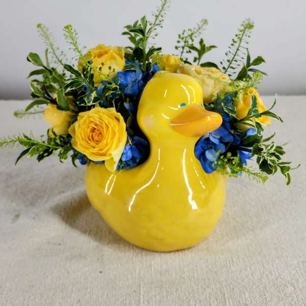 Yellow duck vase with yellow roses and blue flowers