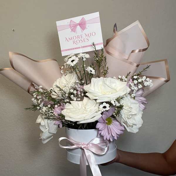 White roses and lavender daisies in a round hatbox with pink ribbon