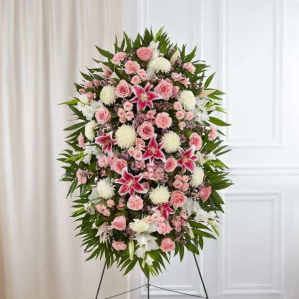 Tall pink and white standing floral spray with lilies, roses, and mums on a metal easel