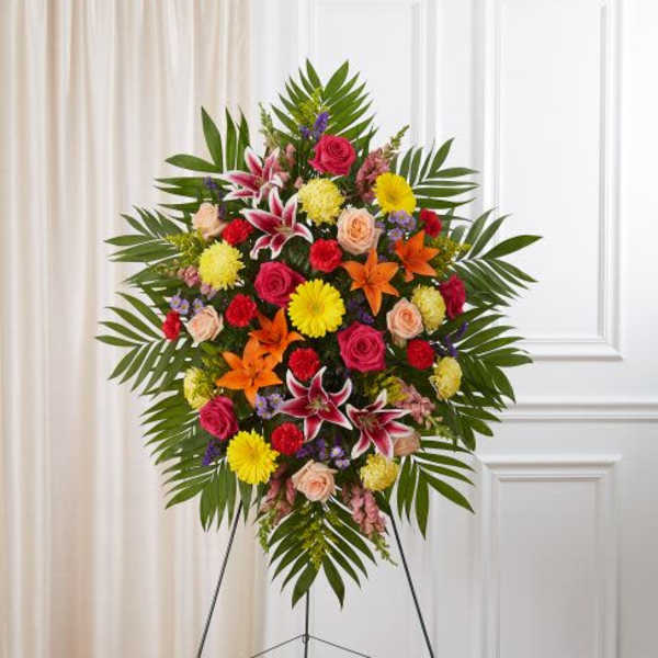 Bright standing spray of mixed pink, yellow, and orange flowers on an easel