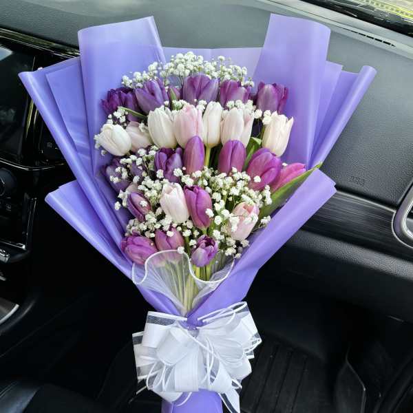 Bouquet of purple, pink, and white tulips wrapped in lavender paper