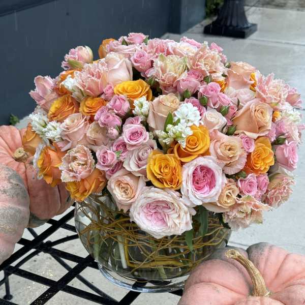 Bouquet of pink, peach, and yellow roses in a glass vase