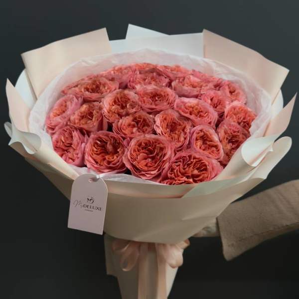 Bouquet of coral-pink roses wrapped in pale paper
