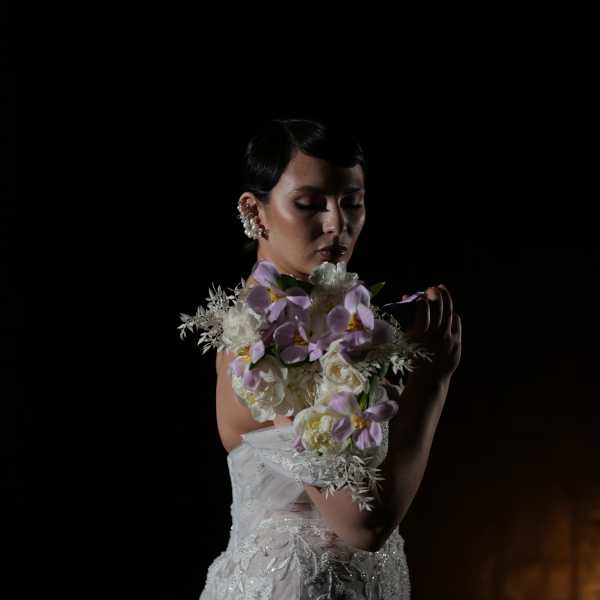 Bride in a white gown holding a lavender and white floral bouquet