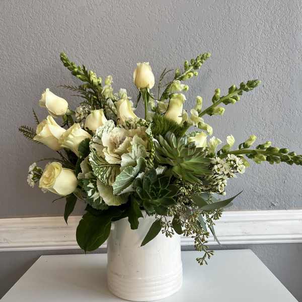 Cream roses and green succulents arranged in a white vase