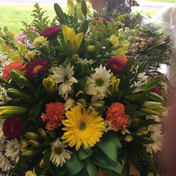 Mixed bouquet with lilies, daisies, and carnations in a basket