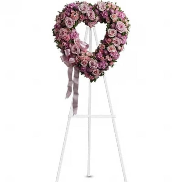 Heart-shaped pink rose wreath on a white easel with ribbon