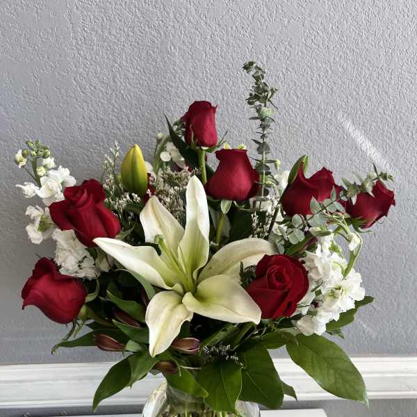 Red roses and white lilies arranged in a clear glass vase