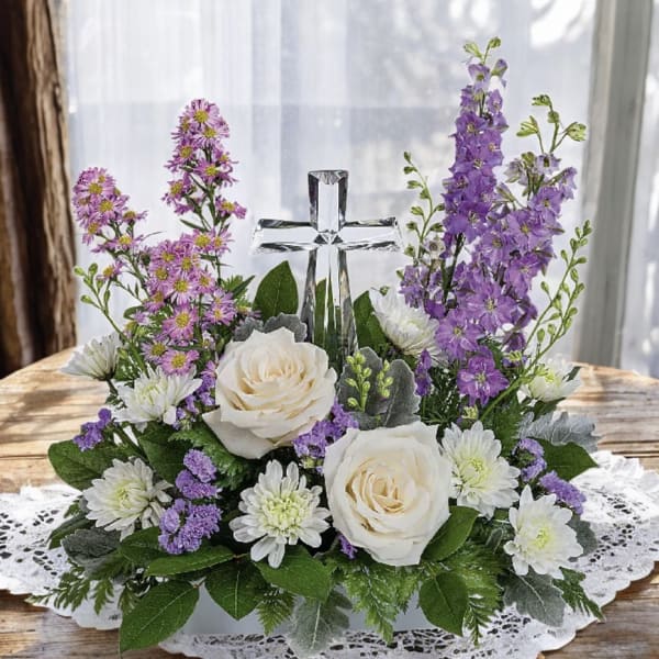 Floral arrangement with white roses, purple flowers, and a glass cross