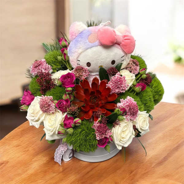 Hello Kitty plush surrounded by pink and white flowers in a round box
