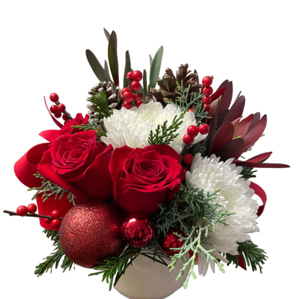 Red roses and white mums in a beige vase with pinecones and ornaments