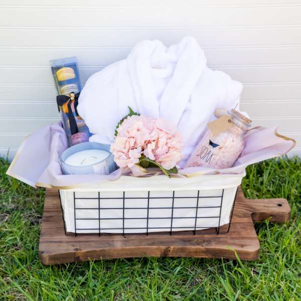 Gift basket with a towel, candle, macarons, soap, and pink flowers
