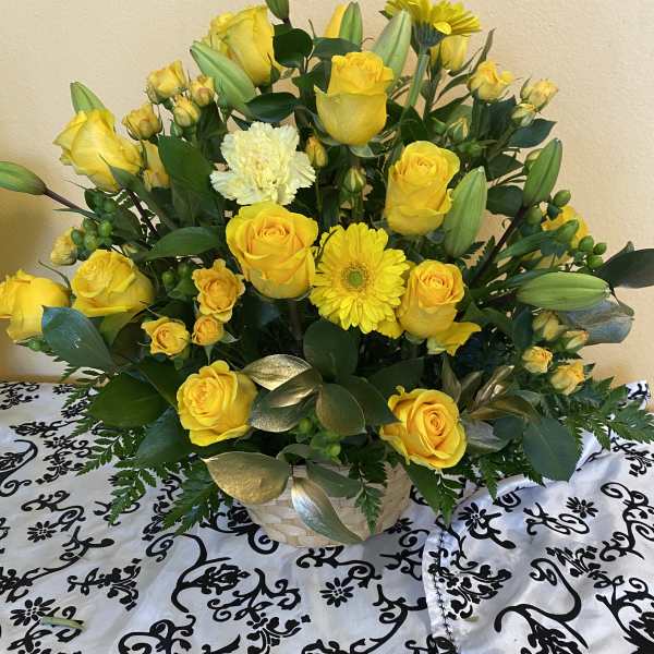 Yellow roses and a yellow gerbera daisy in a basket arrangement