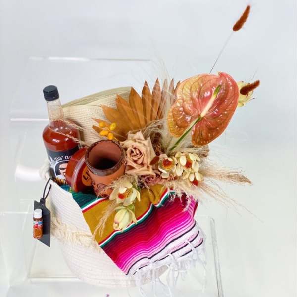 Gift basket with flowers, a bottle, and a colorful woven cloth