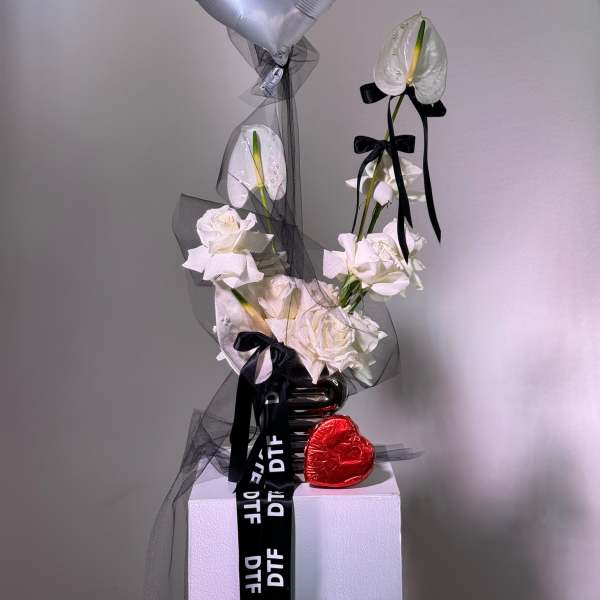 White roses with an anthurium and silver heart balloon on a pedestal