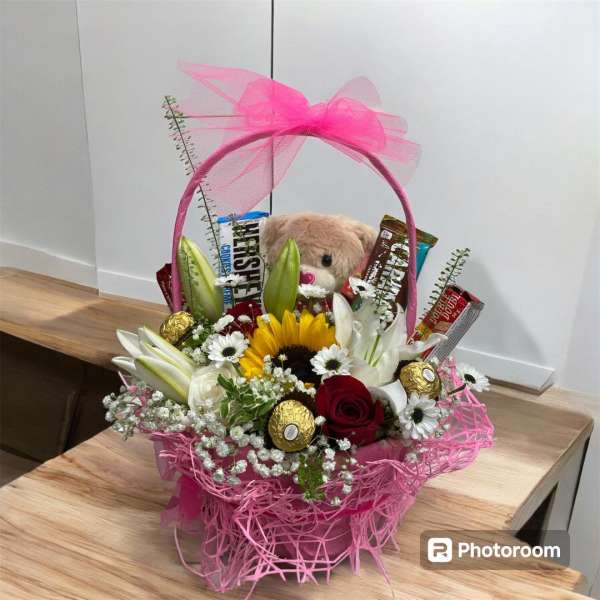 Pink gift basket with flowers, chocolates, and a teddy bear