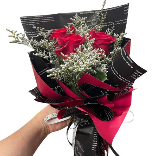 Handheld bouquet of red roses with silver filler and black-red wrapping