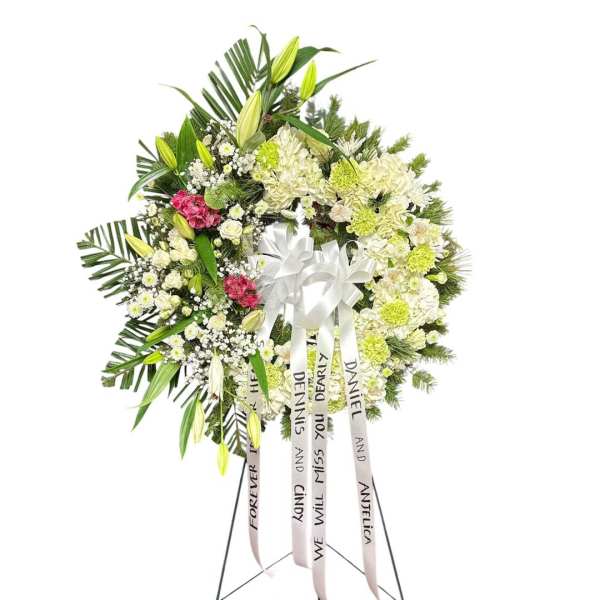 Standing funeral wreath of white and green flowers with ribbon streamers