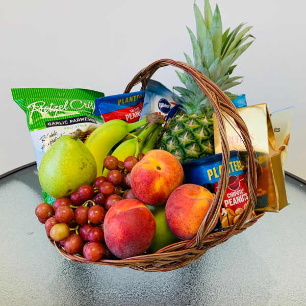 Fruit basket with grapes, peaches, pear, pineapple, bananas, and snack bags
