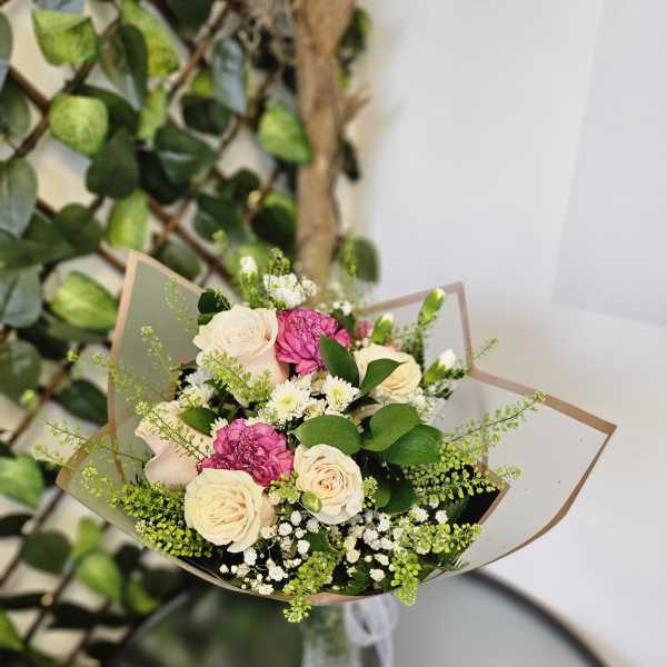 Bouquet of cream and pink roses with small white filler flowers