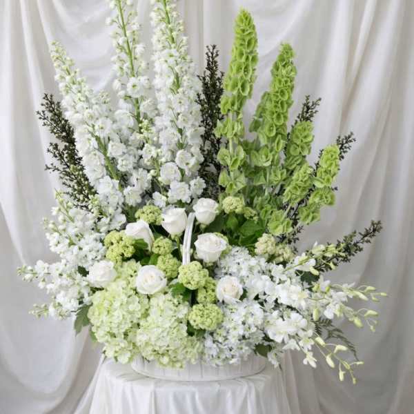 Large white and green floral arrangement in a white container