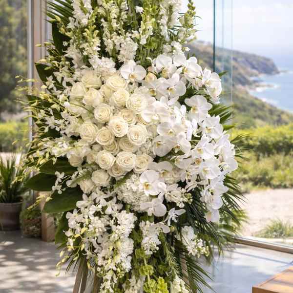 Tall white floral arrangement with roses and orchids on an easel