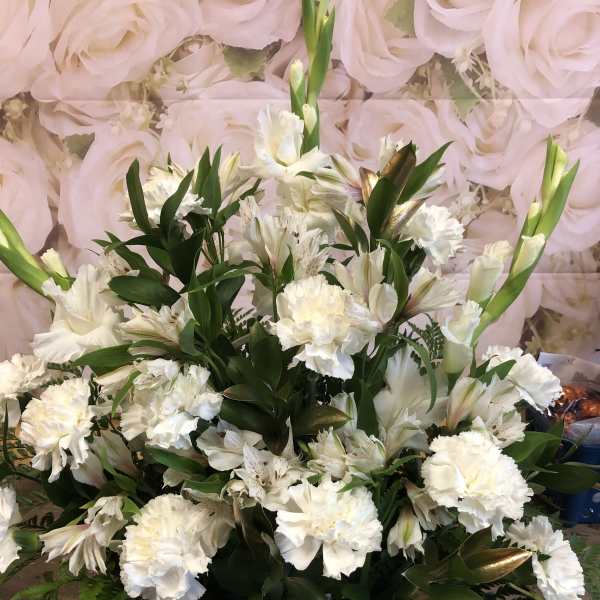 White floral arrangement in a basket with a sheer ribbon bow