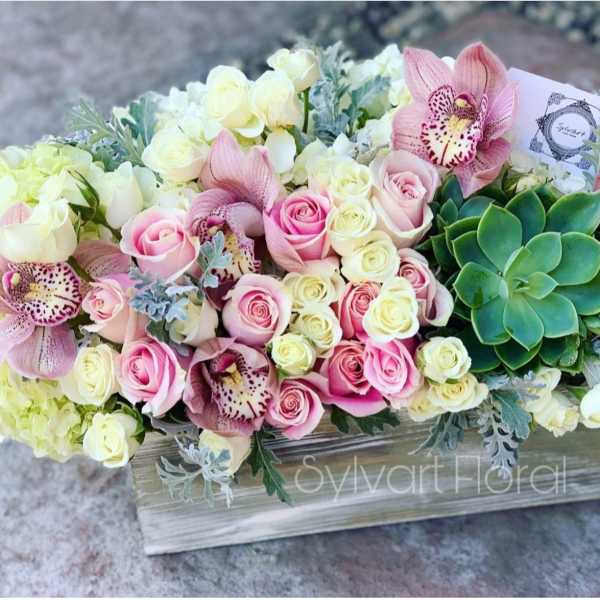 Pink and white roses with orchids and a succulent in a wooden box